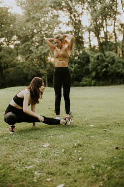 Parkta esneme hareketleri yapan iki sevimli genç bayan.