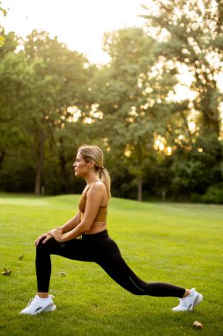Parkta esneme hareketleri yapan güzel bir genç kadın.