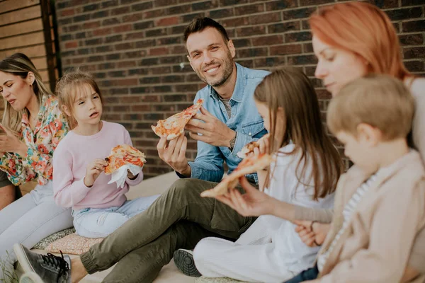 stock image Happy group of young people and kids eating pizza in the house backyard