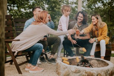 Bir grup arkadaş evin arka bahçesinde mısır pişirip eğleniyorlar.