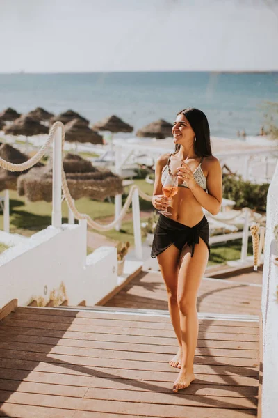 Gülümseyen Genç Kadın Bikini Kokteyl Içerken Tatilin Tadını Çıkarıyor — Stok fotoğraf