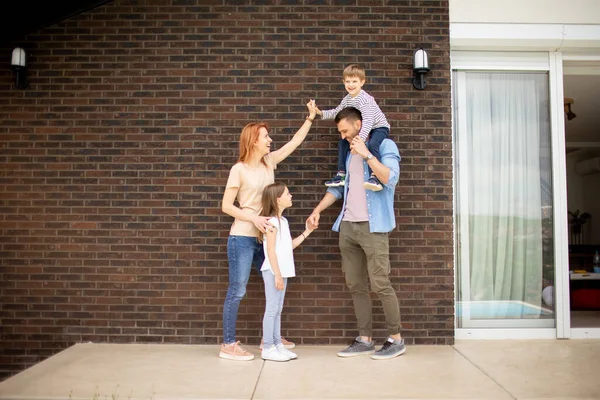 儿子和女儿站在砖房墙边的家庭 — 图库照片