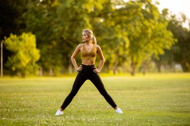 Parkta esneme hareketleri yapan güzel bir genç kadın.