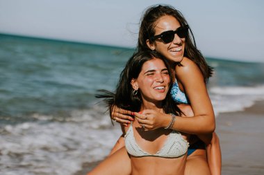 İki güzel genç kadın sıcak yaz gününde deniz kenarında eğleniyor.