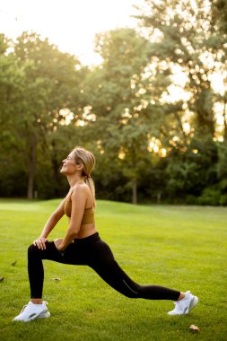Parkta esneme hareketleri yapan güzel bir genç kadın.