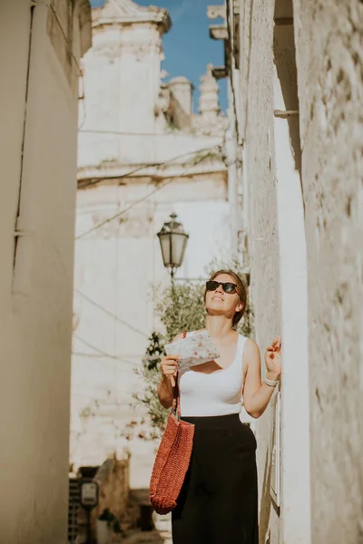 İtalya 'nın dar sokaklarında elinde kağıt şehir haritası olan kadın turist.
