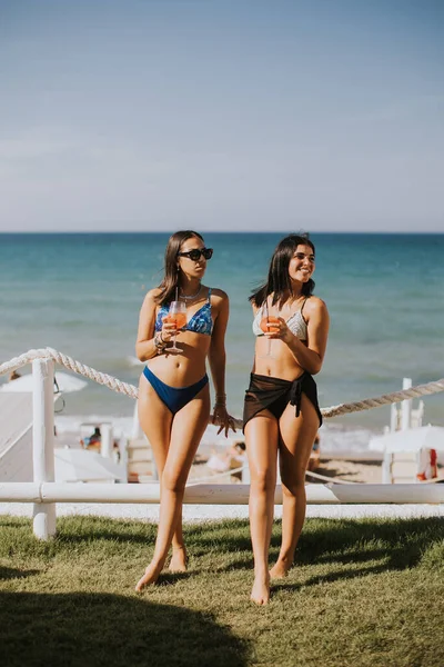 Duas Jovens Sorridentes Biquíni Desfrutando Férias Praia Enquanto Bebem Coquetel — Fotografia de Stock