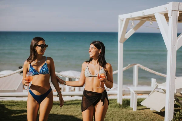 Dos Jóvenes Sonrientes Bikini Disfrutando Vacaciones Playa Mientras Beben Cóctel — Foto de Stock