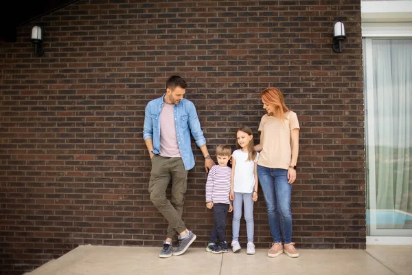 儿子和女儿站在砖房墙边的家庭 — 图库照片