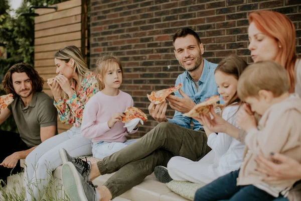 一群快乐的年轻人和小孩在自家后院吃披萨 — 图库照片