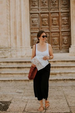 İtalya 'nın Ostuni kentindeki San Francesco d' Assisi kilisesinin şehir haritasına sahip bir kadın turist.
