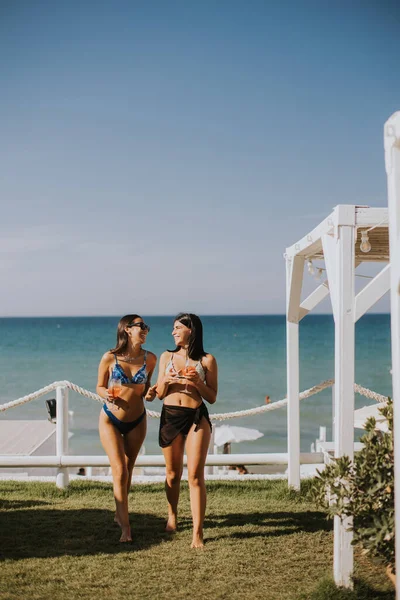 Две Улыбающиеся Девушки Бикини Наслаждаются Отдыхом Пляже Выпивая Коктейль — стоковое фото