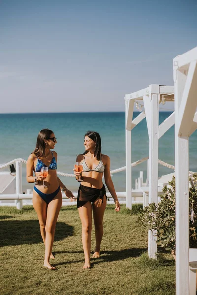 Två Leende Unga Kvinnor Bikini Njuter Semester Stranden Medan Dricker — Stockfoto