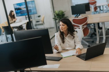 Modern ofiste dizüstü bilgisayarla çalışan güzel bir iş kadını.