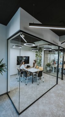 Genç iş kadınları modern ofiste kabinde tartışıyorlar.