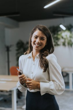 Modern ofiste dijital tabletli genç bir iş kadını duruyor.