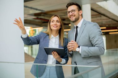 Genç iş çifti dijital tablet tutuyor ve şirket stratejisini tartışıyor