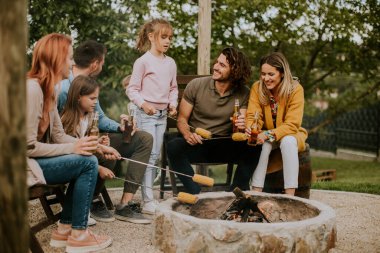 Bir grup arkadaş evin arka bahçesinde mısır pişirip eğleniyorlar.