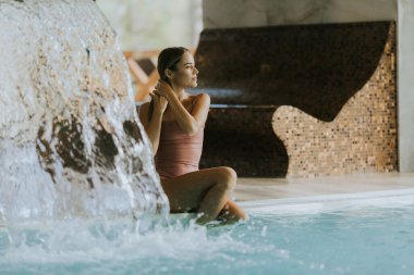 Kapalı havuzda dinlenen genç ve güzel bir kadın.