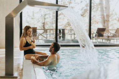 Kapalı havuzda dinlenen yakışıklı genç bir çift.