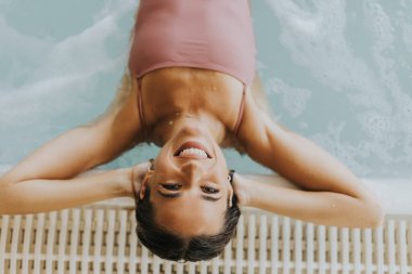 Kapalı yüzme havuzunda dinlenen genç ve güzel bir kadın.