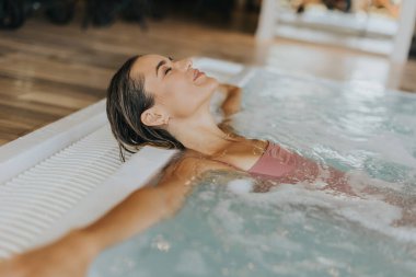 Kapalı yüzme havuzunda dinlenen genç ve güzel bir kadın.