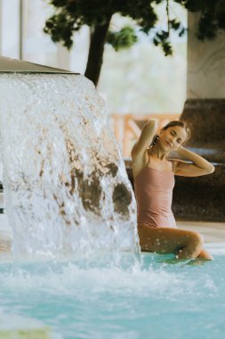 Kapalı havuzda dinlenen genç ve güzel bir kadın.