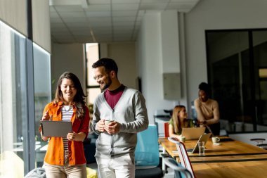 Modern ofiste dijital tabletli genç bir çift takımının önünde duruyor.