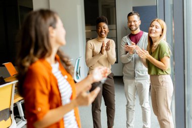 Modern ofiste takımının önünde duran genç bir iş kadını.