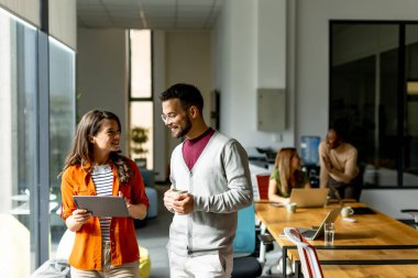 Modern ofiste dijital tabletli genç bir çift takımının önünde duruyor.
