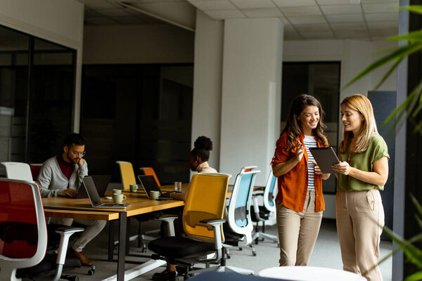 Two pretty young business women with digital tablet in the modern office