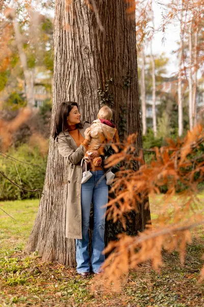 秋の公園でかわいい赤ん坊の女の子を抱えている若い女性 — ストック写真