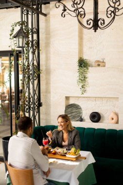 Genç çift yemek yiyor ve restoranda taze sıkılmış meyve suyu içiyor.