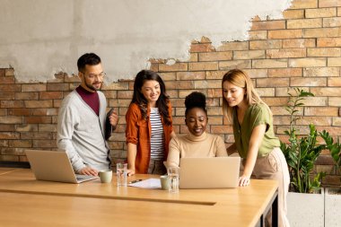 Endüstriyel stil ofisindeki tuğla duvarın yanında çalışan çok ırklı bir grup.