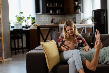 Çiftler, başlarını diğerlerinin kucağına yaslayıp oturma odalarının sıcaklığı ve konforuyla çevrili bir şekilde huzurlu ve hassas bir anı paylaşırlar..