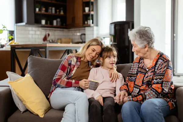 Tři Generace Žen Užívají Smích Konverzaci Pohodlném Gauči Obývacím Pokoji — Stock fotografie