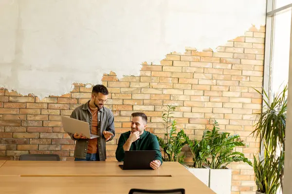 Two Smiling Professionals Engage Collaborative Work Session Wooden Table Camaraderie Stock Photo