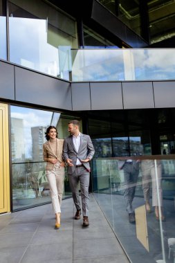 İki profesyonel, çağdaş bir ofisten çıkarken başarıyı yansıtan güven ve mutluluk yayarlar..