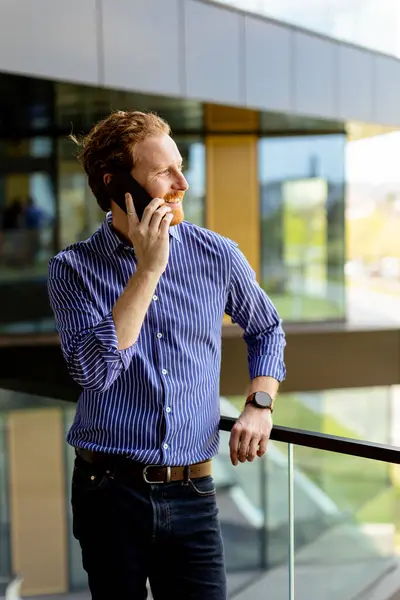 Seorang Pria Terfokus Dalam Kemeja Bergaris Garis Berbicara Telepon Sambil — Stok Foto