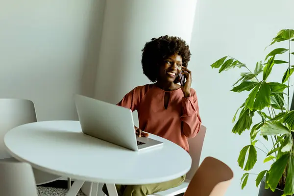 Cheerful Woman Talks Her Phone Cafe Table Laptop Vibrant Plant — Stock Photo, Image
