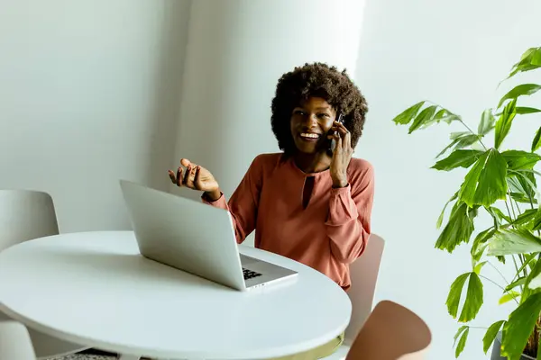 Confident Woman Multitasks Phone Call Laptop Bright Plant Adorned Office — Stock Photo, Image