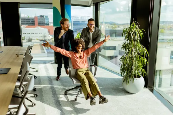 Exuberant Workers Engage Impromptu Office Chair Race Basking Afternoon Light — Stock Photo, Image