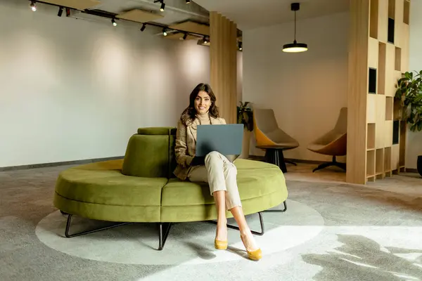 Wanita Terfokus Bekerja Pada Laptop Duduk Sofa Hijau Chic Kantor — Stok Foto