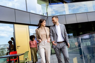 İki profesyonel, çağdaş bir ofisten çıkarken başarıyı yansıtan güven ve mutluluk yayarlar..