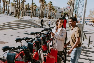 Genç çift, Barcelona 'daki kiralık bir istasyondan bisiklet seçerek keyifli bir gün geçiriyor..