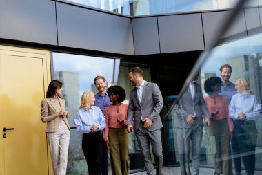 Çağdaş bir ofisin dışında, takım çalışması ve bağlantıyı yansıtan sıradan bir sohbet için toplanan bir grup iş adamı..