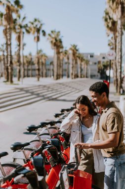 Genç çift, Barcelona 'daki kiralık bir istasyondan bisiklet seçerek keyifli bir gün geçiriyor..