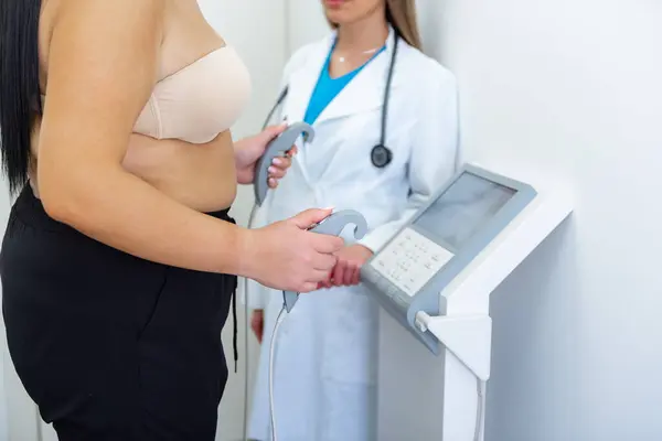 医療従事者は 高度な機器を使用して体組成テストを持つ女性を支援します ストック写真