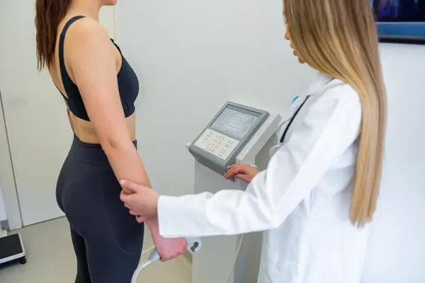 医療従事者は 高度な機器を使用して体組成テストを持つ女性を支援します ストックフォト