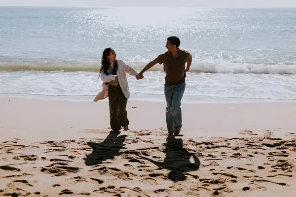 Ein Lächelndes Paar Genießt Einen Unbeschwerten Lauf Einem Sandigen Ufer lizenzfreie Stockbilder